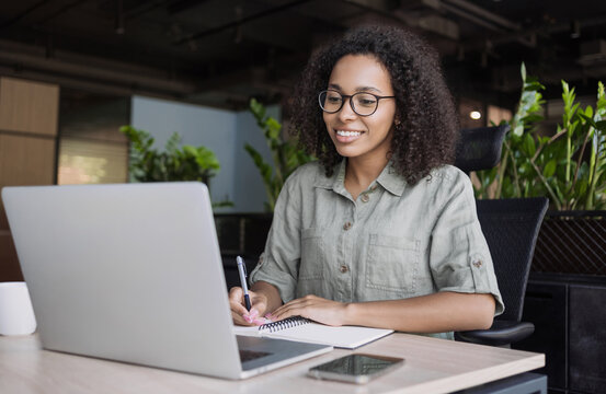 Young woman using laptop computer at office. Student girl working at home. Work or study online, freelance, business, lifestyle concept