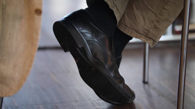 Close Up of Man Sitting with Crossed Legs Wearing Black Leather Shoes