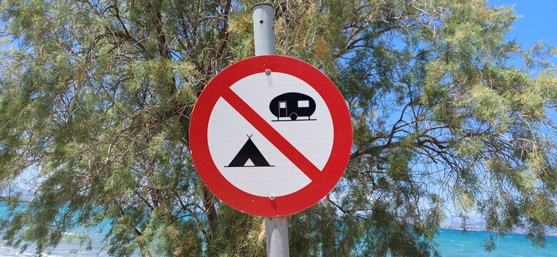 Verkehrsschild mit Campingverbot vor einem Baum und dem Meer in Griechenland