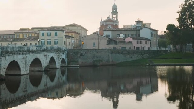 Rimini old town with Tiberius Bridge over Marecchia river at sunrise, Emilia-Romagna, Italy. Italian city with medieval architecture and Ponte di Tiberio. Tourist and travel destination