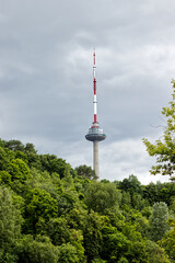 Obraz premium Vilnius, Lithuania June 11, 2026, Vilnius TV Tower rising above a lush green forest on a cloudy summer day