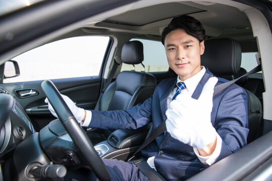 Professional chauffeur giving thumbs up inside a private car
