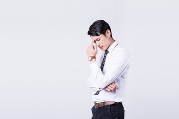 Naklejka premium Stressed young businessman with headache and worry on plain background
