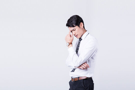 Stressed young businessman with headache and worry on plain background