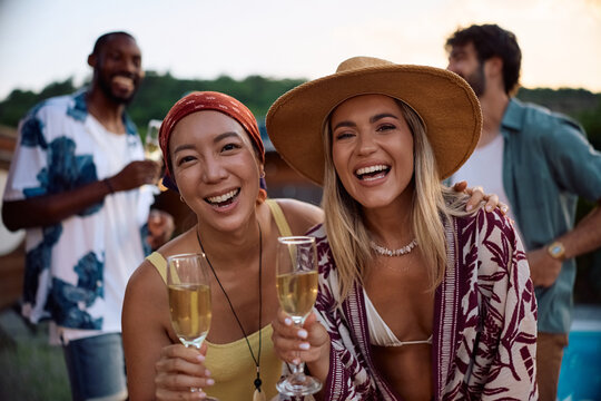 Carefree woman celebrating summer with glass of champagne and looking at camera.