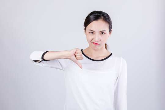Young woman showing thumbs down with displeased expression in studio
