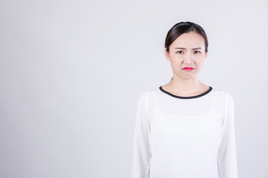 Young woman with displeased expression on plain background