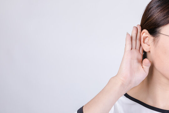 Close-Up Woman Listening with Hand to Ear on Plain Background