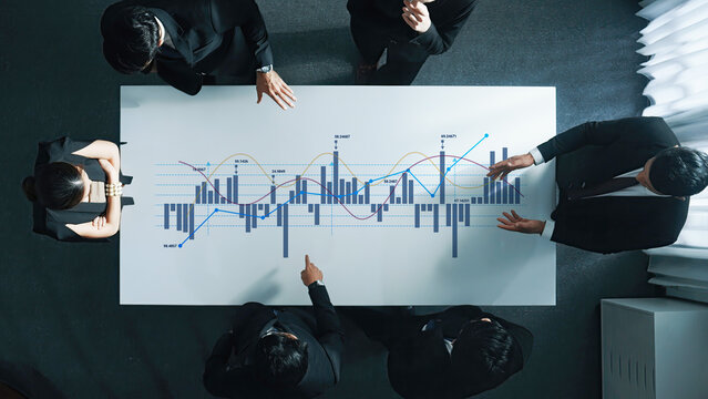 A group of business professionals collaboratively analyzing financial data displayed on a modern office table, highlighting graphs, charts, and trends for informed decision-making. Ledger