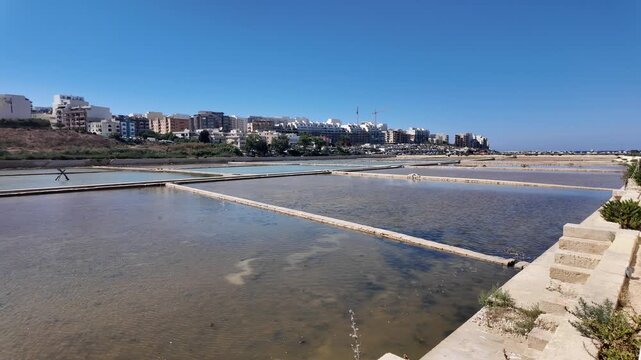 Salina, Malta - 06.07.2026 - Salina Nature Reserve, View of salt pans with buildings to the rear in Salina Bay, Bugibba, Malta.