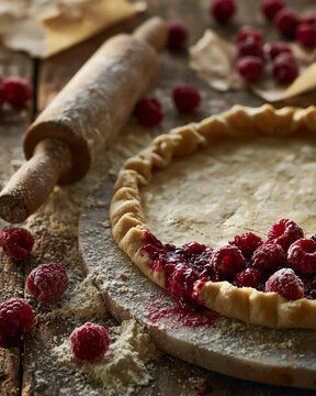 Rustic pie preparation with fresh raspberries on a wooden table