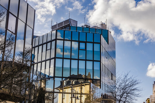Modern glass building reflecting blue sky and old architecture