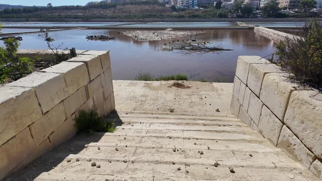Salina, Malta - 06.07.2026 - Salina Nature Reserve, View of salt pans with buildings to the rear in Salina Bay, Bugibba, Malta.