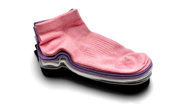 Photo of a neat stack of colorful low-cut ankle socks, a multi-colored pack of five casual trainer socks including pink, purple, white, grey, and black, isolated on white background.