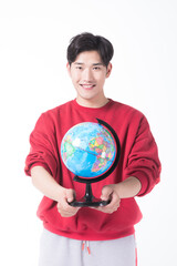 Fototapeta premium Smiling young man holding a world globe on white background