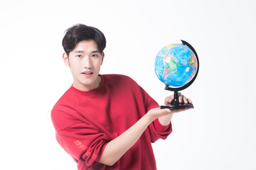 Fototapeta premium Young man holding and presenting a world globe on white background