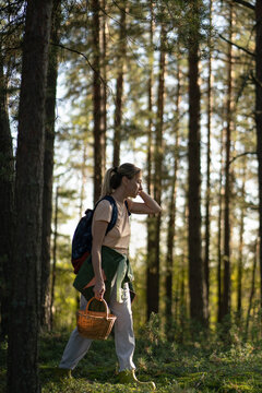 Woman searcher foraging in nature, walking in forest with basket harvesting mushrooms and plants, sustainable hobby and natural food harvest, female finder exploring woodlands gathering fungi.