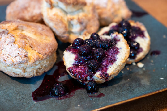 Homemade biscuits on a square platter, split open and topped with hand crafted blueberry sauce, delicious summer food treat
