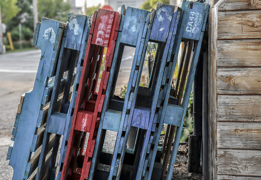 Different coloured wooden pallets leaning against a wooden  wall, nobody
