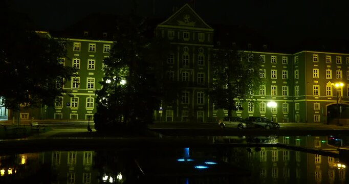 Illuminated Pond Reflecting Szczecin City Hall at Night - Jasne Błonia Square in Szczecin, Poland, at approximately 1:45 a.m. Gently rippling water in an illuminated pond reflects the lights