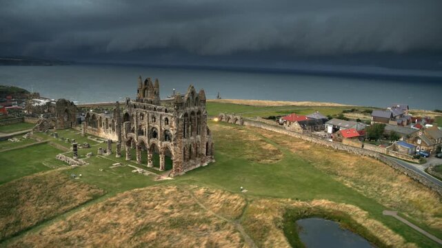 Aerial footage showing the historic Whitby Abbey ruins with a stormy sea and dark clouds approaching