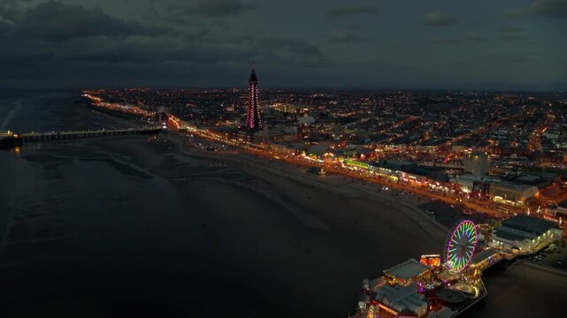 Aerial view of the Blackpool Tower and illuminations at night, showing the beach and city lights