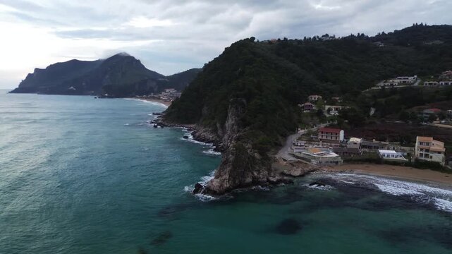 Kontogialos Beach, Pelekas, Corfu, Ionian Islands, Greece. Aerial drone footage of the rocky coastline, sandy beach and Ionian Sea under dramatic clouds after a storm.