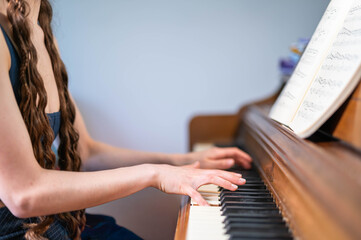 Person Playing Piano While Reading Sheet Music on an Acoustic Upright Piano © Slizo