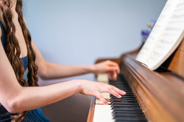 Person Playing Piano While Reading Sheet Music on an Acoustic Upright Piano © Slizo