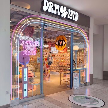 Photo of the vibrant, neon-lit storefront of the DRM-LND custom jewelry and DIY bead shop at Fisketorvet Mall in Copenhagen, Denmark.