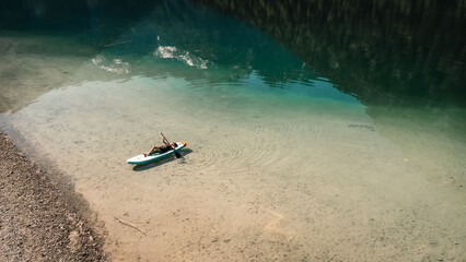 Small fishing boat anchored in shallow turquoise coastal bay beside pebble beach and clear sandy seabed, seen from aerial viewpoint with calm water, soft sunlight, and remote peaceful scenery © Anastasia