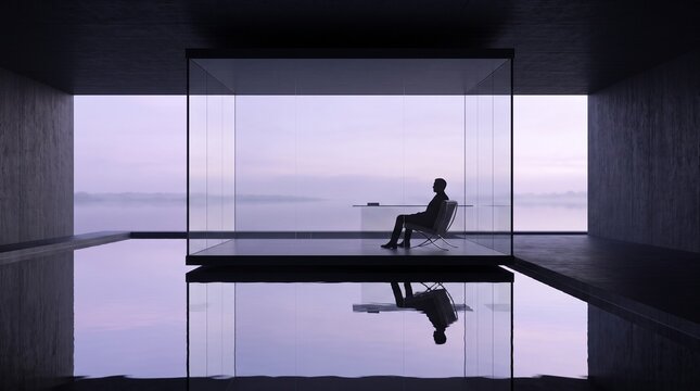 Silhouette of Businessperson Sitting at Desk Overlooking Calm Water at Sunset