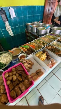 Traditional Indonesian food buffet display in a local warung restaurant featuring various savory dishes curry chicken tempeh tofu