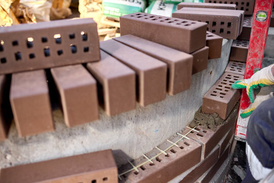 construction worker carefully applying mortar to bricks on a building site, focused and industrious mood, close-up of the bricklaying process, brown and gray bricks, concrete bricks, masoni.