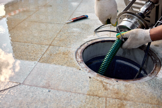 removal of manhole cover on sidewalk with concrete and metal materials, practical ground-level view, gray and green tones, utility maintenance in construction setting.