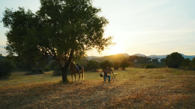 A man drinks a soft drink during a break in the countryside at sunset in Italy
