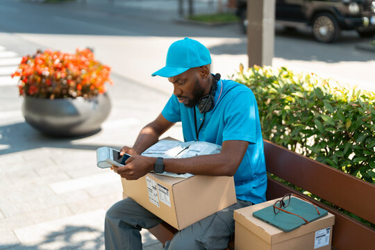 Delivery worker checks a handheld scanner after encountering a technical issue during parcel delivery.