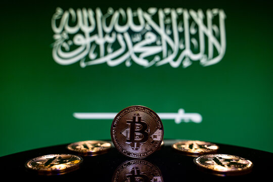 Close up of Bitcoin coins with Saudi Arabia flag background.