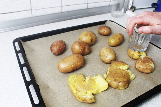 Cooking crispy roasted smashed potatoes . Tramples boiled potatoes on a baking sheet