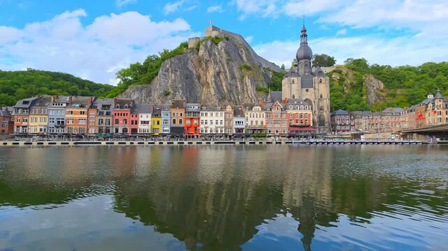Beautiful idyllic town of Dinant, Belgium. Reflections in a rippling river with citadel and gothic church.