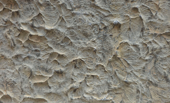 Close up view of rough grey stucco wall with uneven texture and decorative finish on plaster surface showing artistic details