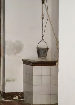 Historic water well with metal bucket inside traditional Spanish house located in an old apartment space