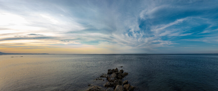 Bright sky over the Mediterranean Sea with clouds during the evening near the shore at a coastal location
