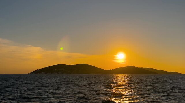 Silhouette of the Princes Islands at sunset, view from a moving ferry on the Marmara Sea. Golden sun reflects on rippled water, dramatic sky and calm evening atmosphere in Istanbul