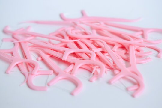 Macro close-up view focusing on a cluttered stack of pink plastic dental flossers on a white background.