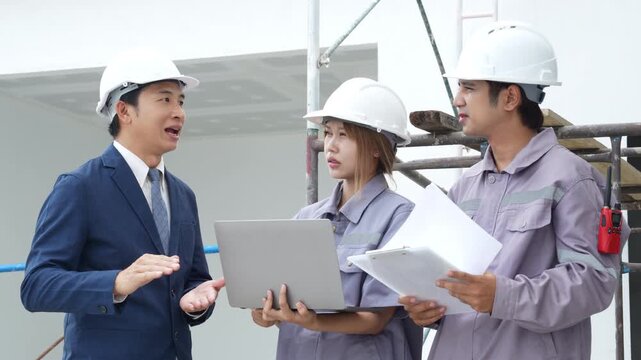 Construction engineers in safety helmets inspecting a residential building exterior, reviewing site progress, scaffolding and project management during an on-site construction inspection.