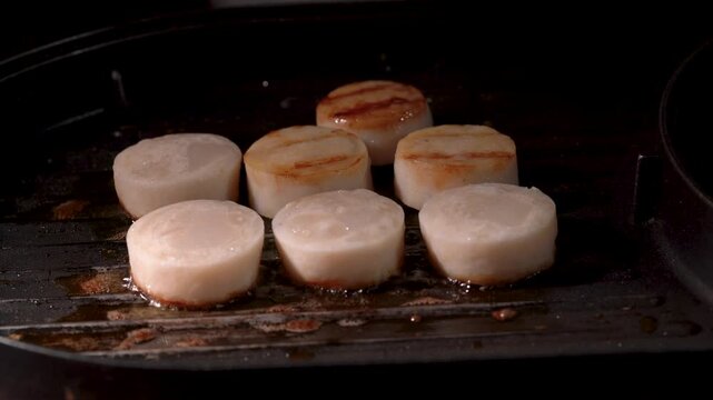 A close-up video of fresh scallops grilled on the half shell over high heat until perfectly cooked.
