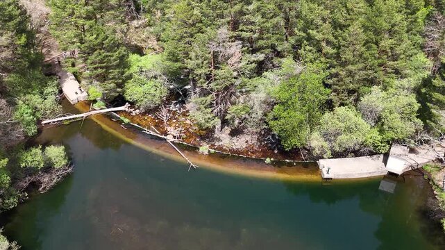 Aerial drone footage of Presa del Pradillo on the Rio Manzanares in El Pardo, Madrid, Spain, with hikers on a footbridge and water cascading over the dam