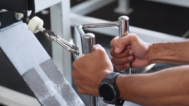 Close-up of a man gripping cable machine handles during strength training, highlighting fitness, resistance exercise, gym equipment and workout performance.