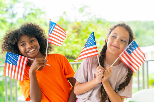 Fourth of July celebration with diverse children girl holding American flags for United States Independence Day expressing patriotism freedom national pride unity community spirit holiday happiness